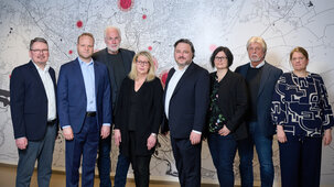Die Mitglieder des KAIFU-Aufsichtsrates stehen gemeinsam nebeneinander vor einer großen Wandgrafik mit einem Stadtplan.